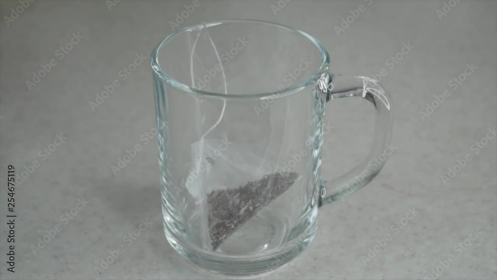Making herbal tea with teabag in transparent mug. Slow motion Making herbal tea with teabag in transparent mug. Slow motion