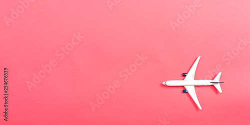 A toy airplane on a pink paper background