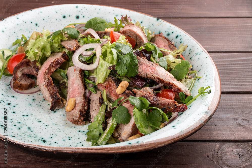 Salad with roast beef and cherry tomatoes on a wooden background Salad with roast beef and cherry tomatoes on a wooden background