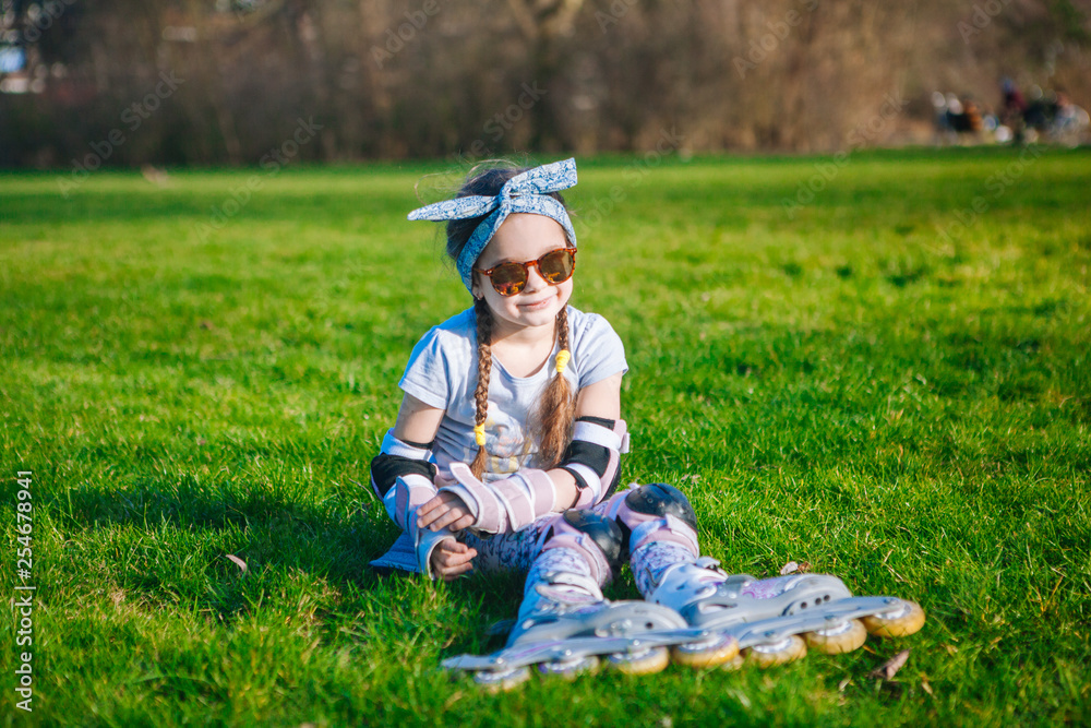 Cute curly girl funny sitting in roller skates and sunglasses and looking at the camera. Cute curly girl funny sitting in roller skates and sunglasses and looking at the camera.