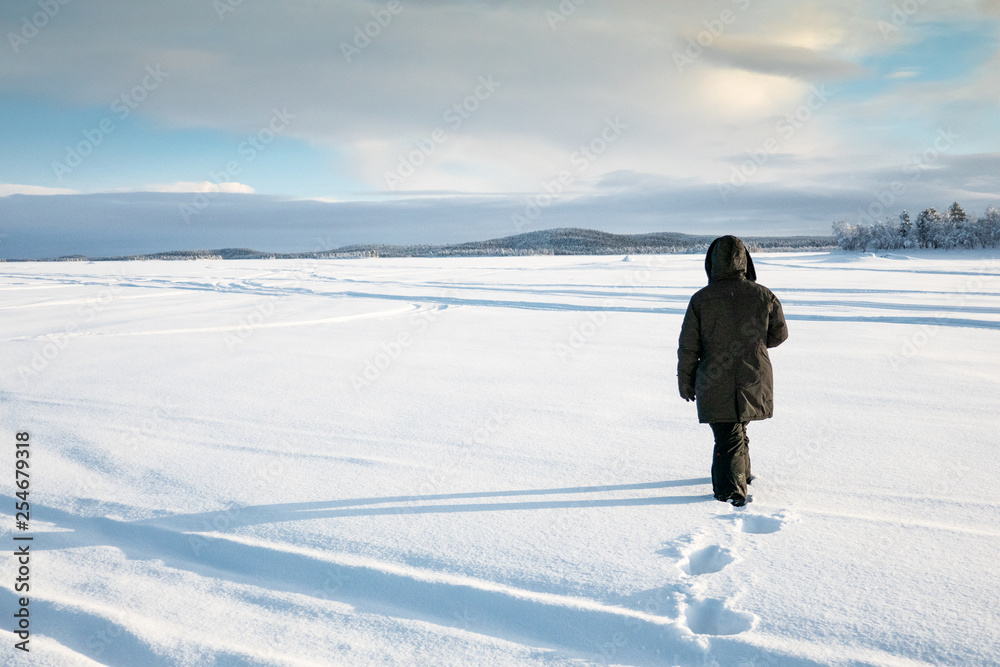 Eine Frau geht auf dem zugefrorenem Inarisee