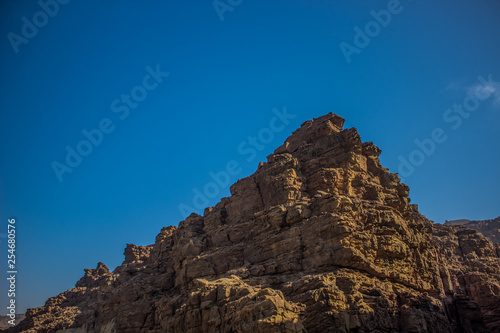 contrast summer bright scenery landscape steep rock in own shadow foreshortening from below on empty vivid blue sky background 