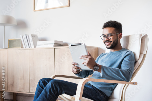  Young man using digital tablet at home. Handsome student resting t in his room. Home work or study, freelance concept