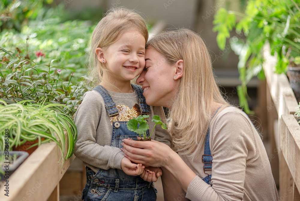 Obraz premium A young woman with a small daughter is planting a plant in a pot.