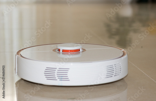 Close-up: Modern Robot Vacuum Cleaner Working Under Low Table in House. Concept: Smart Home. 