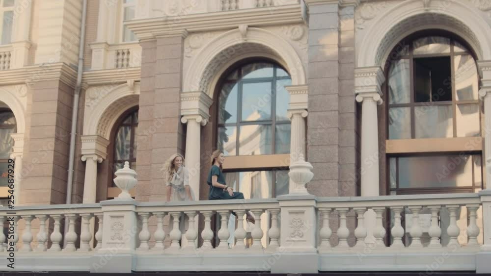 Two models of the girl sit on the gothic railing. Urban fashion. Two models of the girl sit on the gothic railing. Urban fashion.