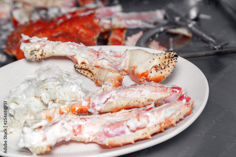 Closeup round white dish with fresh red big boiled prepared blue kamchatka crab. Concept useful seafood in a menu premium restaurant preparing, serving for guests, clients Closeup round white dish with fresh red big boiled prepared blue kamchatka crab. Concept useful seafood in a menu premium restaurant preparing, serving for guests, clients