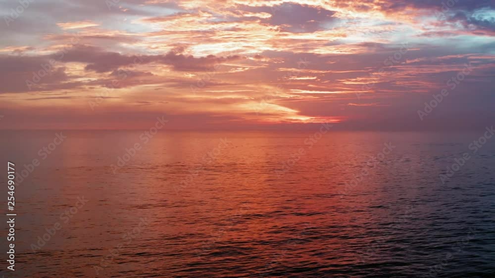 Fly in sunset time. Beautiful red sky, clouds,sea. 4K Aerial panorama. Ocean, sea surface in sunrise, sunset time with beautiful clouds and sun reflection in water