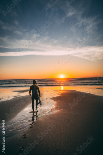 Surfer getting in the water at sunset