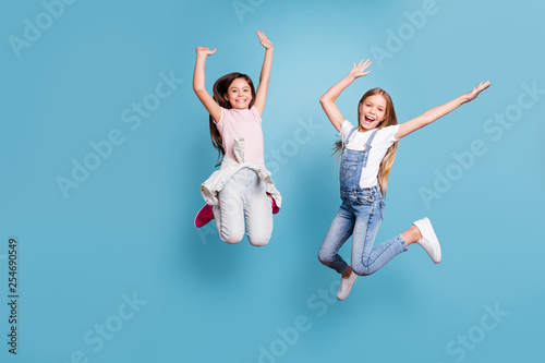 Full length body size view of two people nice lovely attractive charming cheerful careless glad straight-haired pre-teen girls having fun party overjoy cool day isolated on blue pastel background