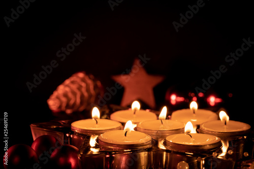 Christmas decoration with seven burning candles in front of dark background