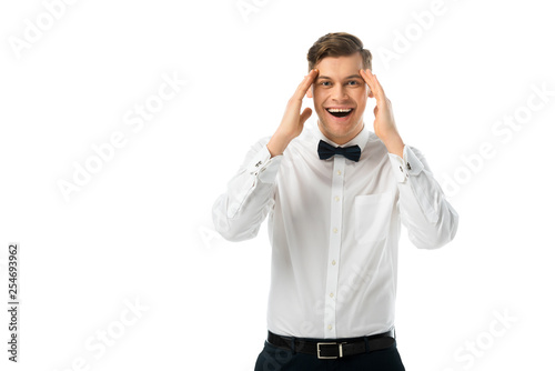 cheerful bridegroom holding hands near head isolated on white