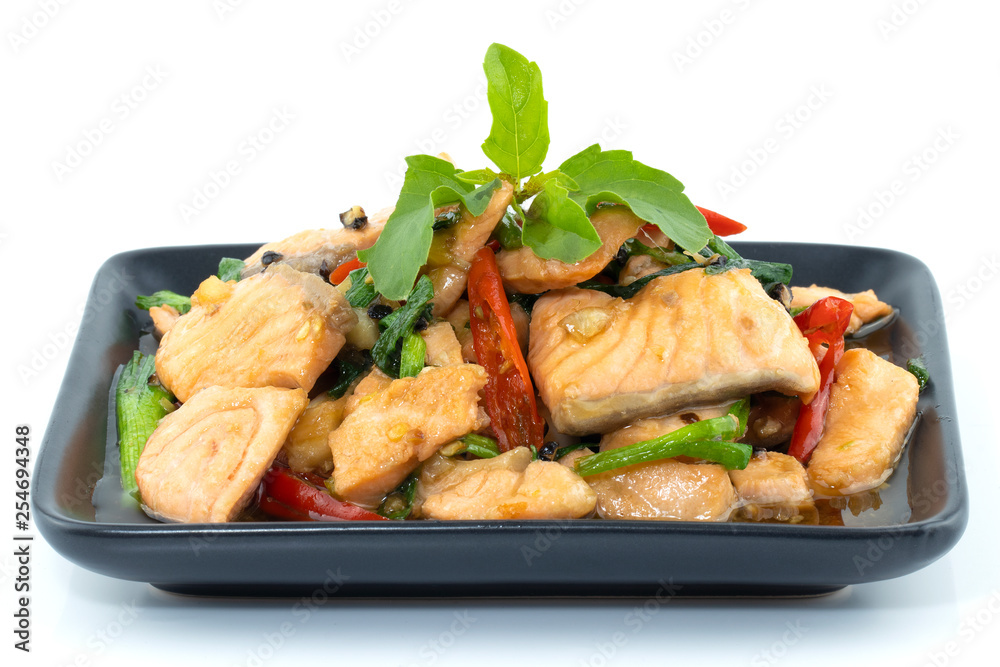 Stir-fried salmon and basil in black dish isolated on white background Stir-fried salmon and basil in black dish isolated on white background