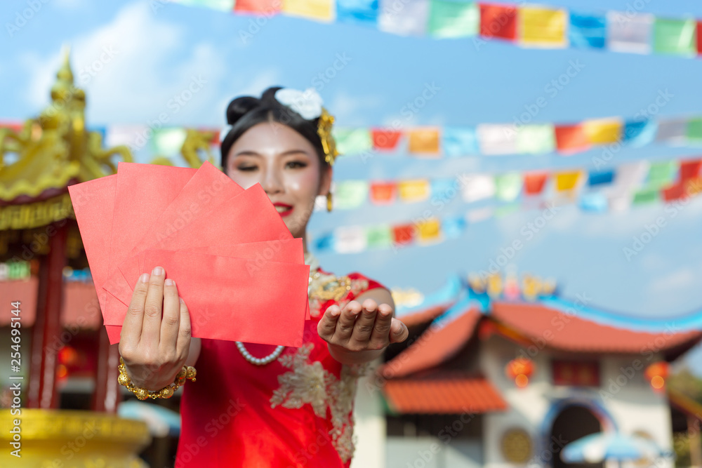 Naklejka premium A beautiful asian girl wearing a red dress holding paper fan in her hand and smiling makes her look happy.