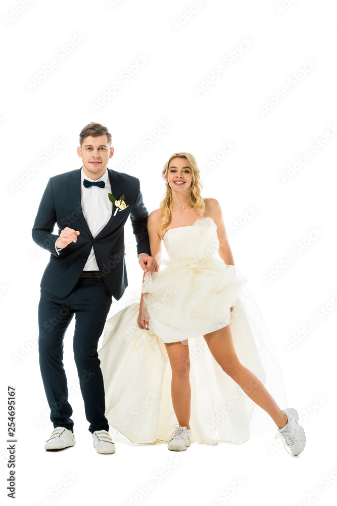 happy groom and bride in elegant clothes and sneakers dancing while looking at camera isolated on white happy groom and bride in elegant clothes and sneakers dancing while looking at camera isolated on white