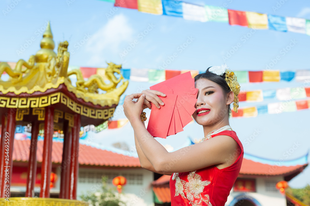 A beautiful asian girl wearing a red dress holding paper fan in her hand and smiling makes her look happy.