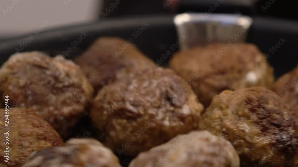 Close-up of meatball cooking and rolling in a pan, slowmotion, looking delicious Close-up of meatball cooking and rolling in a pan, slowmotion, looking delicious