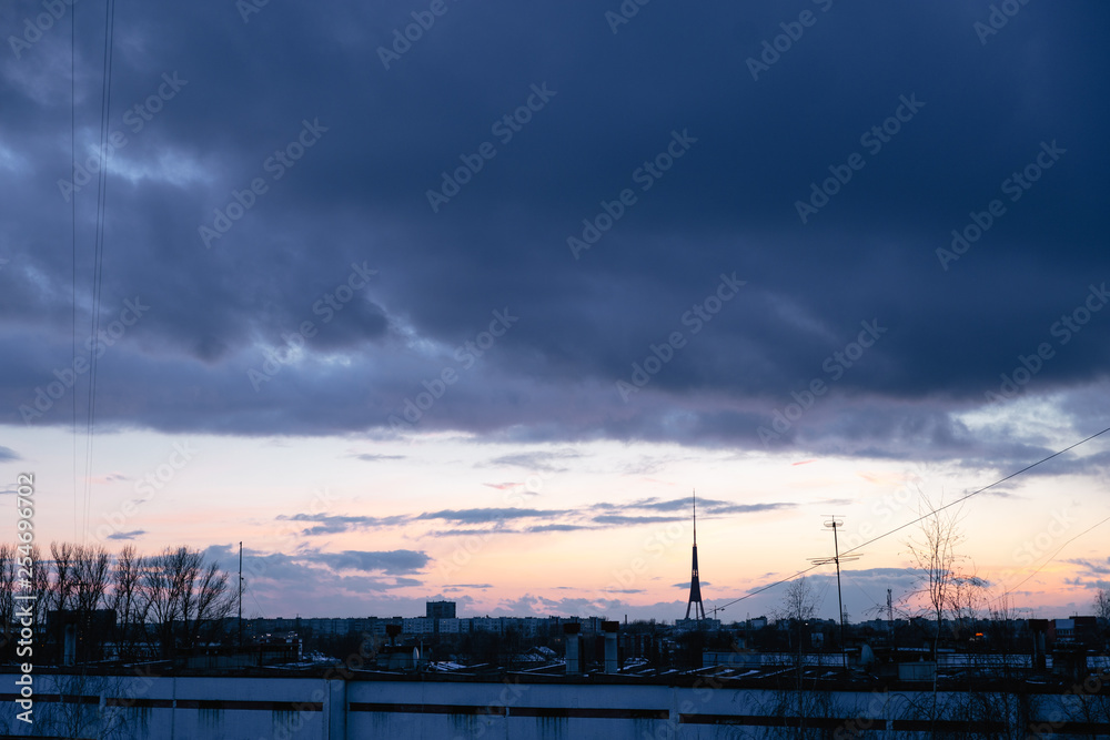 Cityscape with wonderful varicolored vivid dawn. Amazing dramatic blue sky with purple and violet clouds above dark silhouettes of city buildings. Cityscape with wonderful varicolored vivid dawn. Amazing dramatic blue sky with purple and violet clouds above dark silhouettes of city buildings.