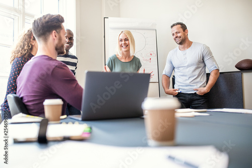 Smiling group of coworkers talking together after an office pres