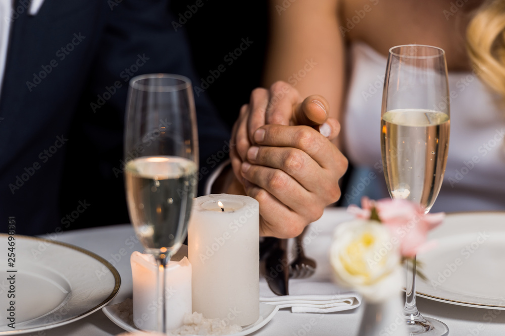 selective focus of man and woman holding hands while sitting at served table on black background