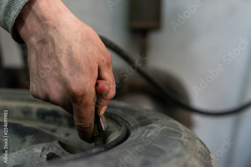 A professional worker in a service station pumps the pressure of the wheels of a car.