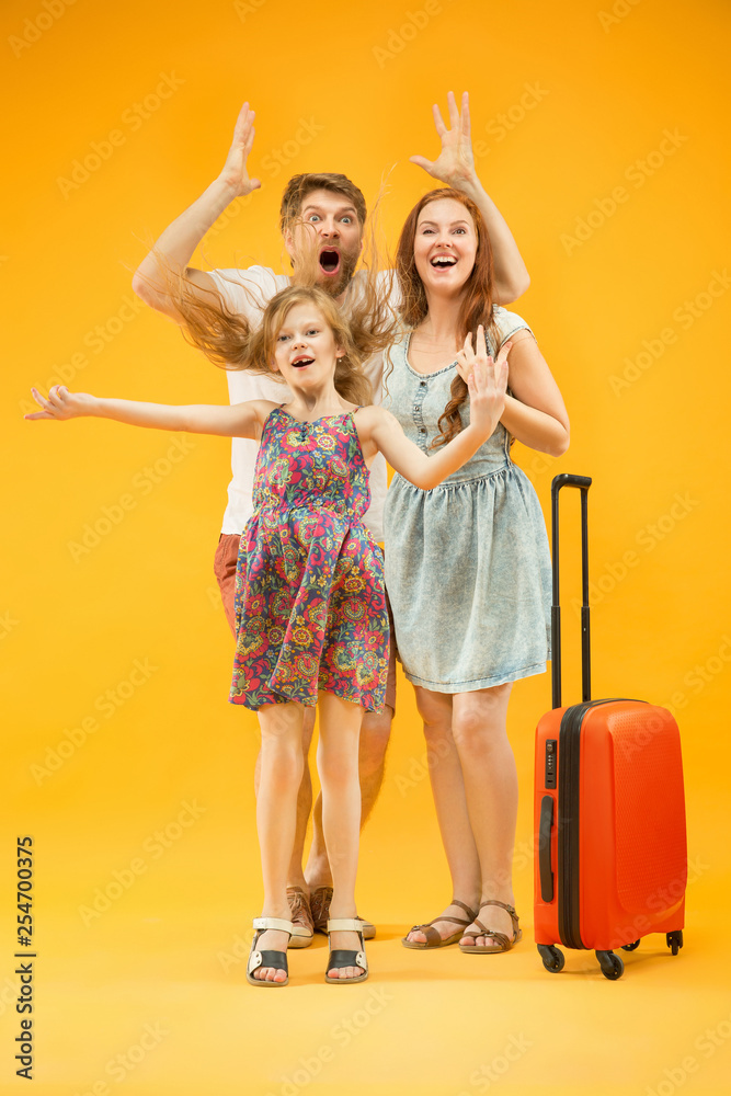 Happy surprised parent with daughter and suitcase at studio isolated on yellow background. Travel, vacation, parenthood, togetherness, tourism concept. Happy surprised parent with daughter and suitcase at studio isolated on yellow background. Travel, vacation, parenthood, togetherness, tourism concept.