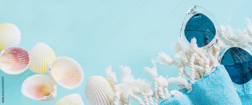 Summer creative concept. Minimal style with transparent glasses, palm leaves, beach towel and seashells on turquoise background with copy space. Long wide banner. Summer creative concept. Minimal style with transparent glasses, palm leaves, beach towel and seashells on turquoise background with copy space. Long wide banner.