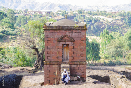 Lalibela, Amhara Region, Ethiopia - Jan 14, 2014: Priest with the holy book in hands sitting on the steps of the Selassie Chapel. photo