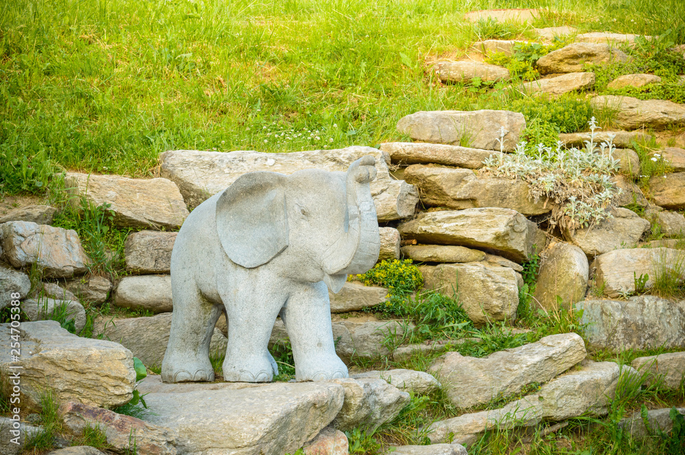 A stone elephant standing on a tourist path.