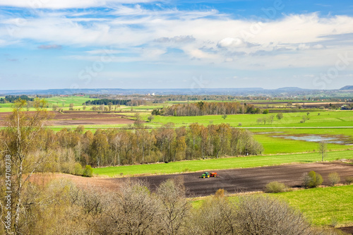 Beautiful landscape view with a tractor on a field in the spring
