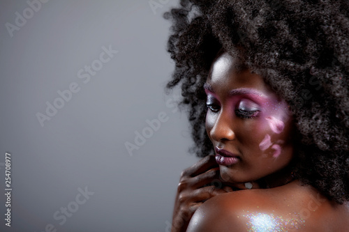 Afro and Flower beauty with big black hair smooth dark skin does stunning poses for studio photography shoot