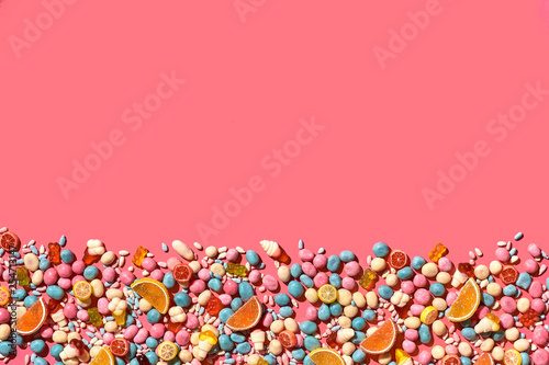 Various sweets, candys are palced on the photo on the coral background © nazarovsergey