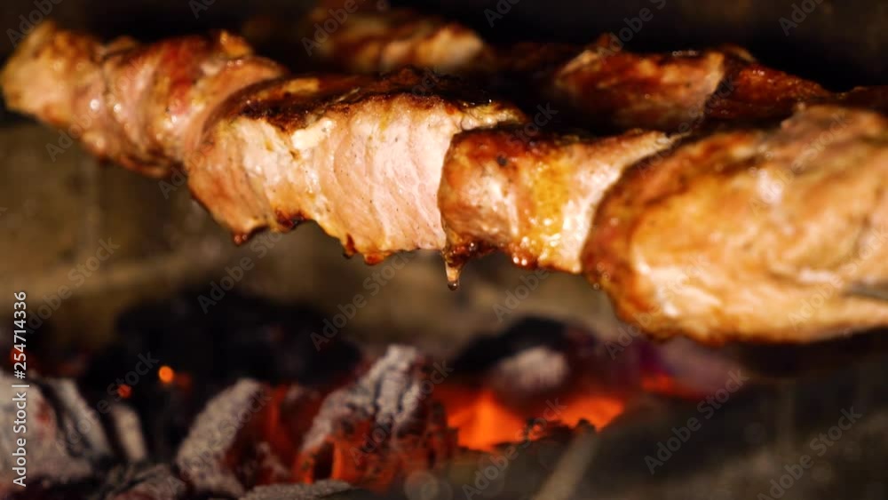 closeup of turning meat skewers while roasting on charcoal grill closeup of turning meat skewers while roasting on charcoal grill