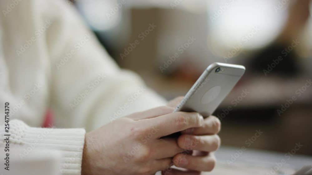 Adult man typing a message on smartphone in a cafe Adult man typing a message on smartphone in a cafe