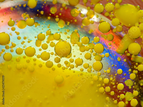 Scores of yellow paint drops on multicolour background. Close up macro shot. Blurred background. Selective soft focus. Colorful abstract universe. Glittering yellow spheres