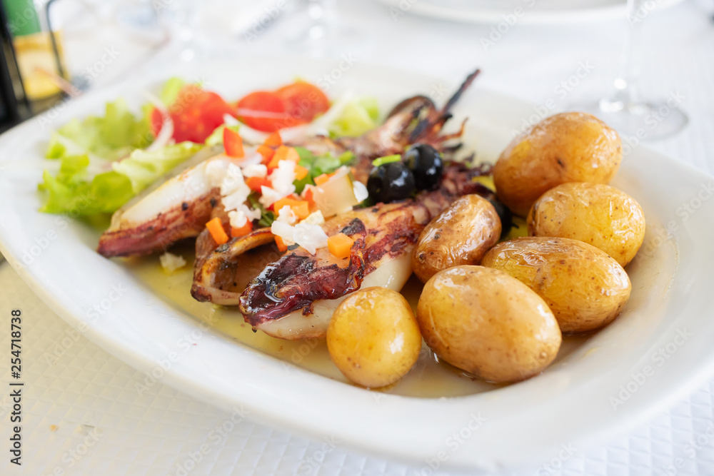 grilled squid with potato and salad on white dish