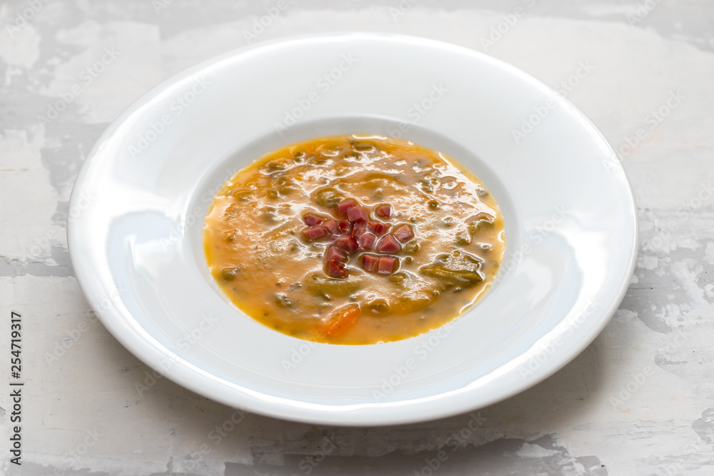 soup with smoked meat in white plate on ceramic dish