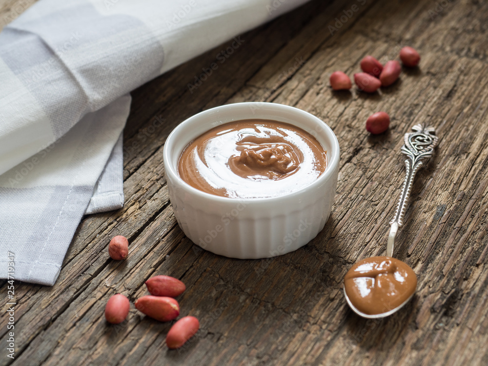 Peanut butter in a white bowl on a wooden table. Natural healthy nutrition and organic food Peanut butter in a white bowl on a wooden table. Natural healthy nutrition and organic food
