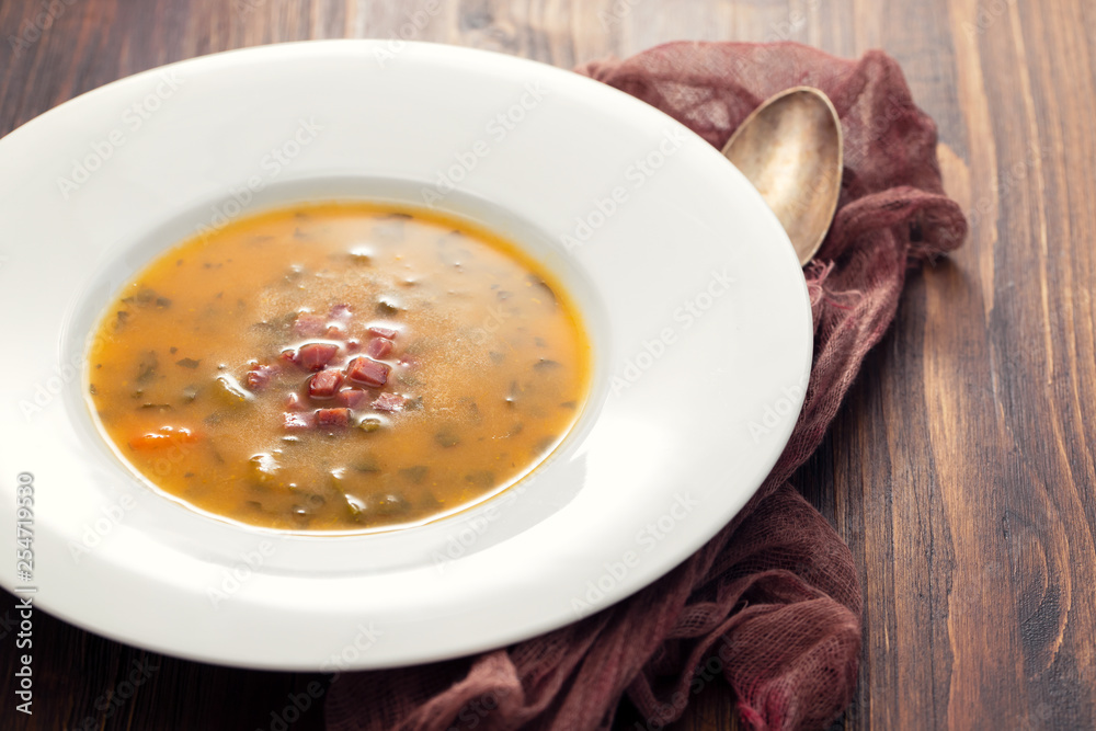 soup with smoked meat in white plate on wooden dish