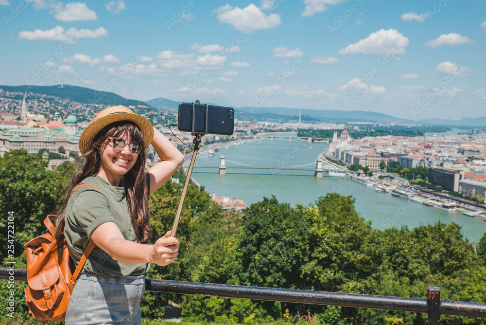 Fototapeta premium smiling cheerful woman in sunglasses taking selfie. budapest city on background