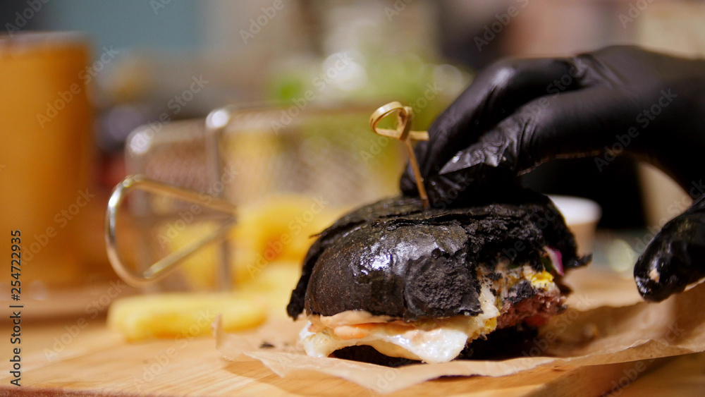 Bitten black burger with bacon and bbq sauce on a wooden desk Bitten black burger with bacon and bbq sauce on a wooden desk
