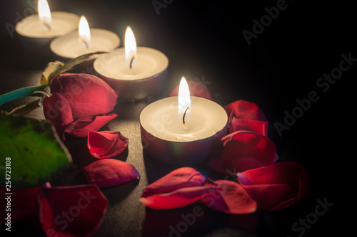 Four tea candles and rose petals in the dark