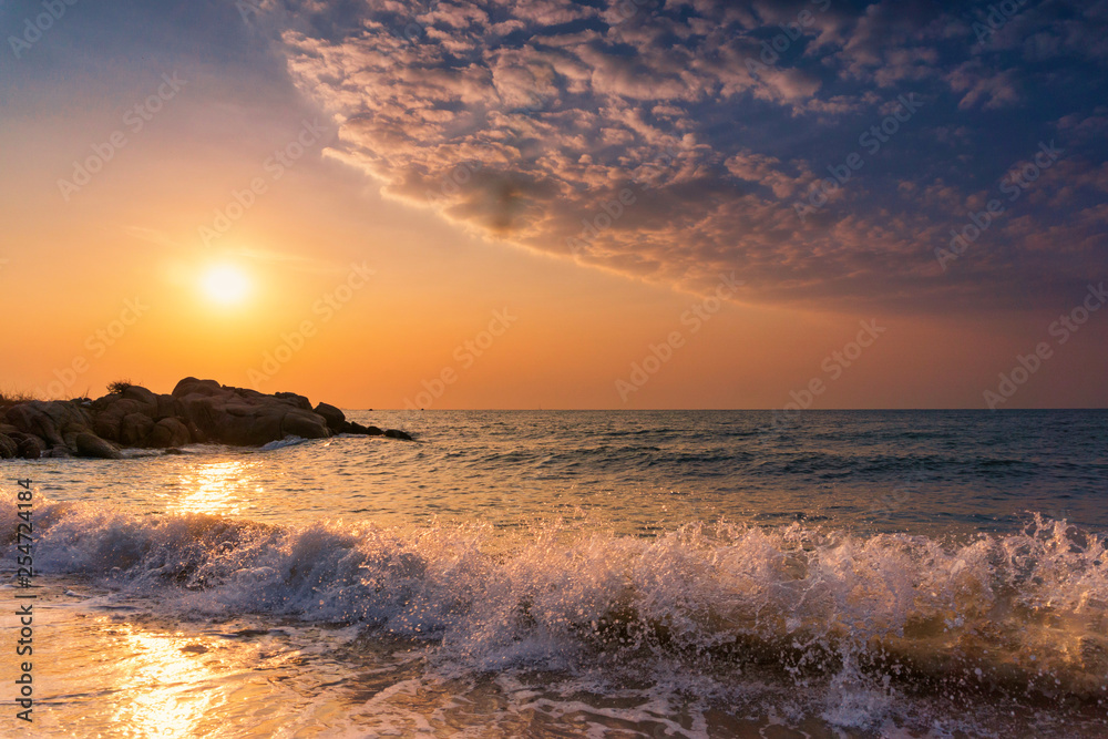 Tropical  sea  ocean waves  splash over the sand on the beach with yellow sky