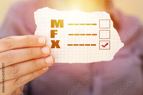 closeup of a young caucasian person holding a form with the letters M for male, F for female and X for the third gender category, written in it, with a check mark on the X photo