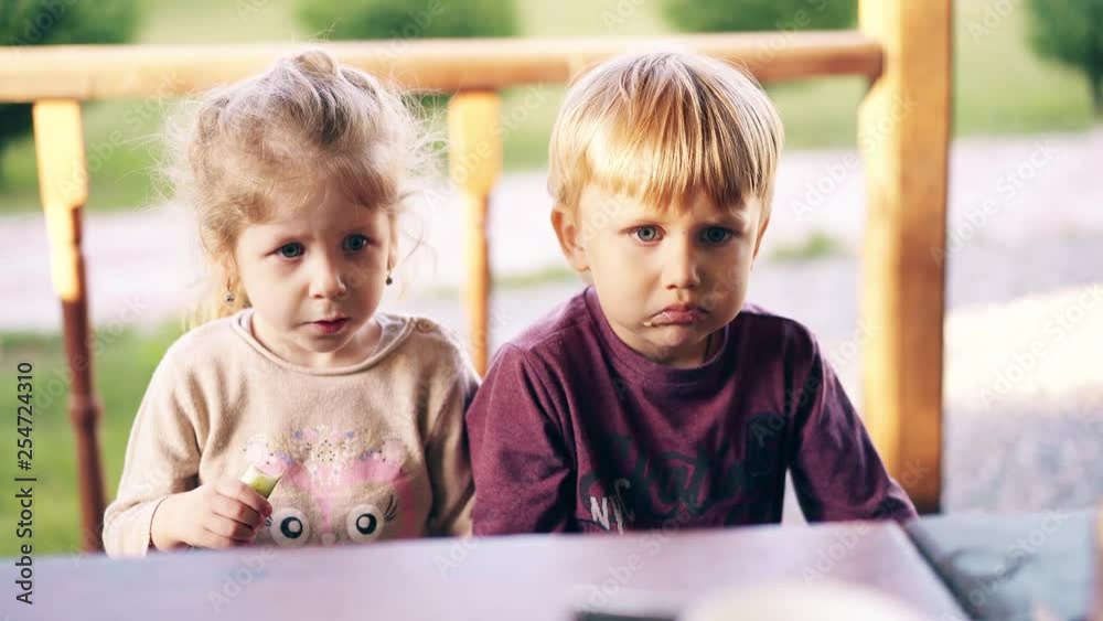 Close-up: Children sit in summer house and eat. Mom feeds them with vegetables.
