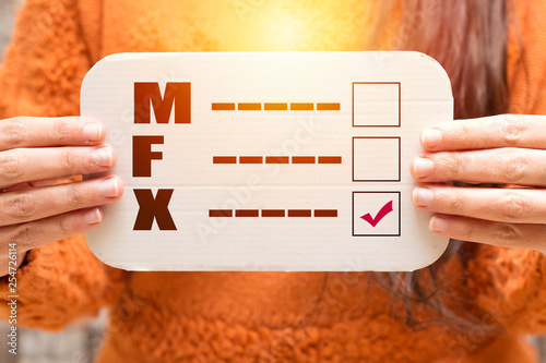 closeup of a young caucasian person holding a form with the letters M for male, F for female and X for the third gender category, written in it, with a check mark on the X photo