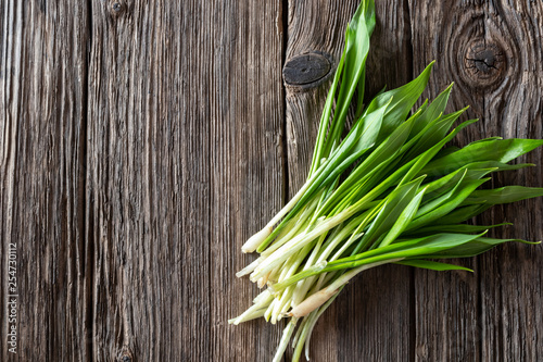 Фотография Fresh wild garlic leaves on a wooden background