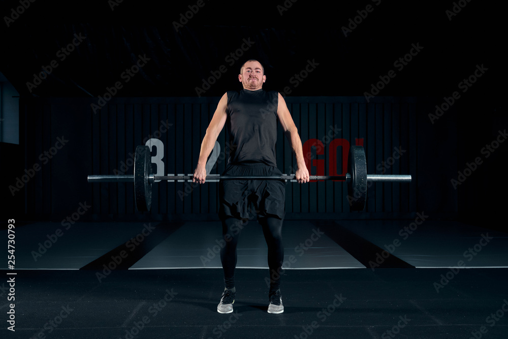 Young man with barbell flexing muscles and making shoulder press lunge in gym Young man with barbell flexing muscles and making shoulder press lunge in gym