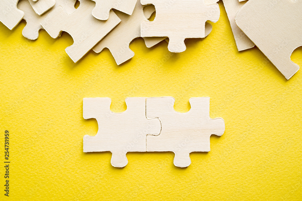 Fototapeta premium Wooden puzzles on a yellow background, close-up, soft focus
