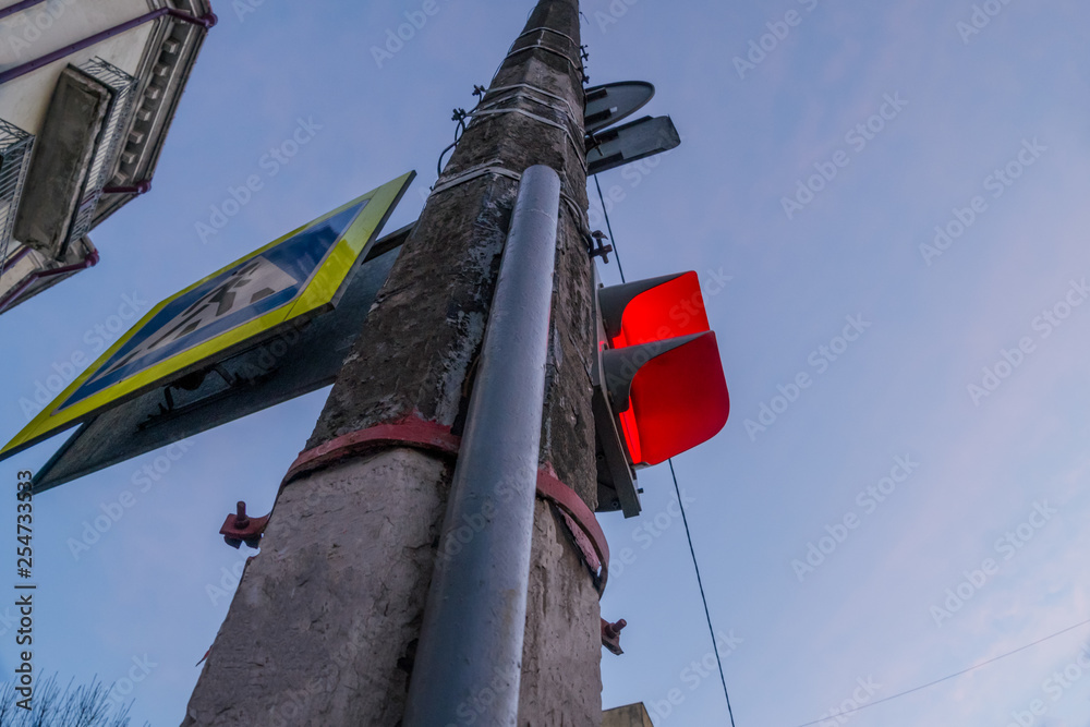 The red traffic light and a pedestrian crossing sign with blue skies in the background.